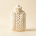 Hot water bottle in a cream cable knit cover