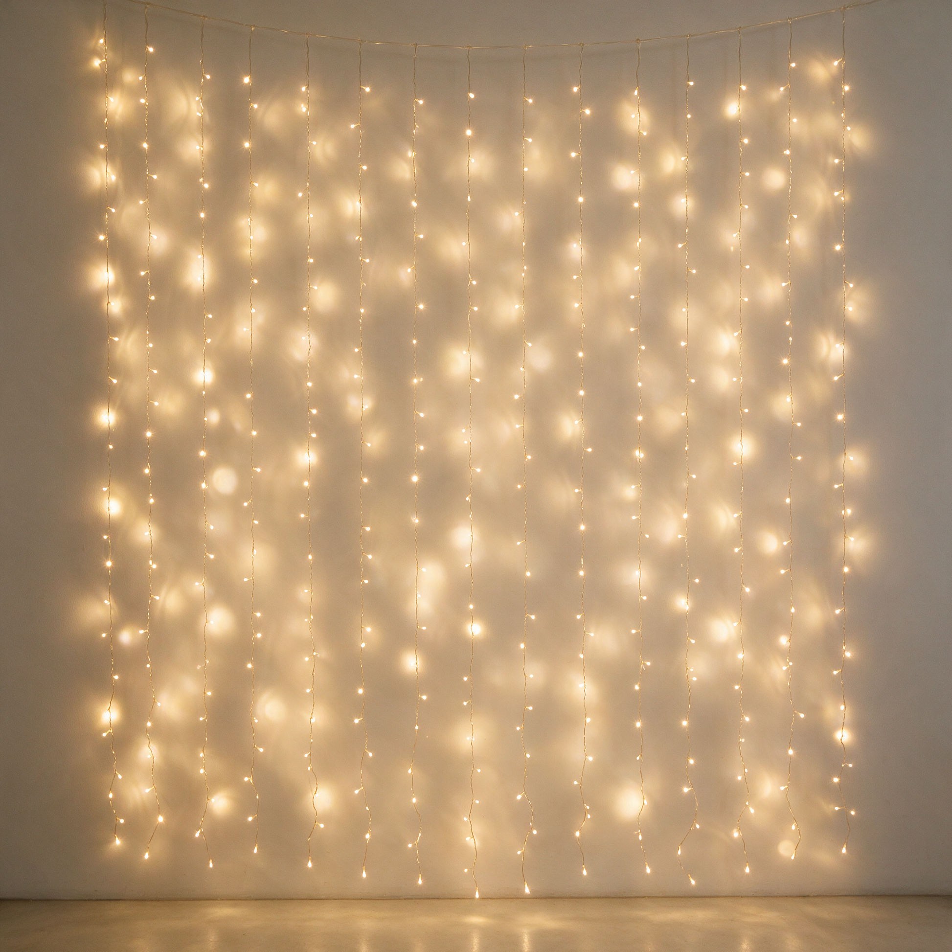 Warm white LED curtain lights glowing against a pale wall