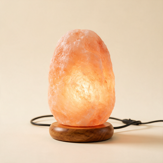 The Glow Himalayan pink salt lamp glowing amber on a wooden base